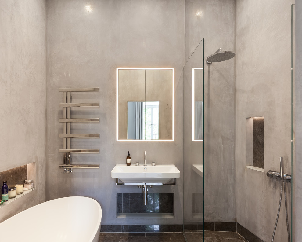 Photo of a mid-sized contemporary 3/4 wet room bathroom in London with a freestanding tub, grey walls, a wall-mount sink, black floor, an open shower, flat-panel cabinets, brown cabinets, a one-piece toilet, multi-coloured tile, glass sheet wall, light hardwood floors and wood benchtops.