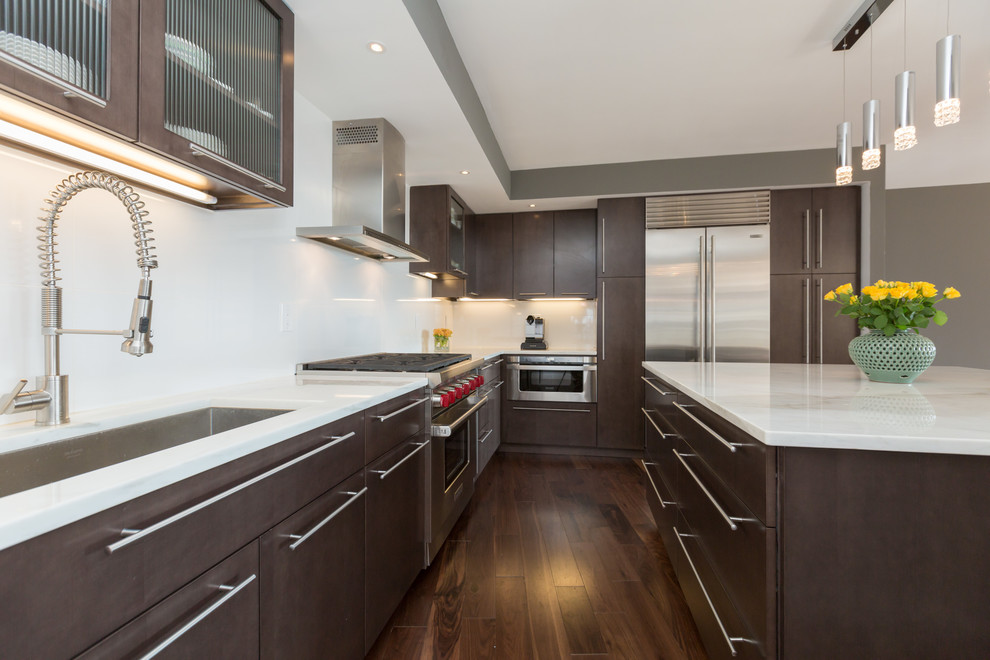 Photo of a large modern l-shaped eat-in kitchen in DC Metro with an undermount sink, flat-panel cabinets, dark wood cabinets, marble benchtops, white splashback, porcelain splashback, stainless steel appliances, medium hardwood floors and with island.