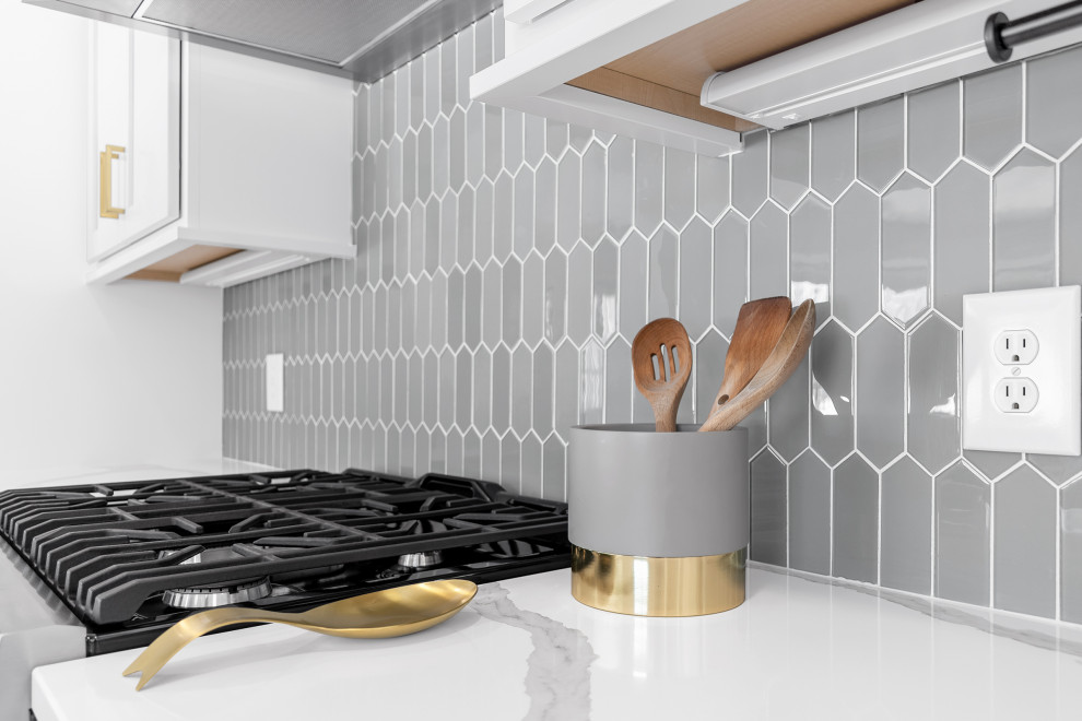 Example of a mid-sized transitional l-shaped light wood floor and brown floor eat-in kitchen design in Minneapolis with an undermount sink, recessed-panel cabinets, gray cabinets, quartz countertops, gray backsplash, glass tile backsplash, stainless steel appliances, an island and white countertops
