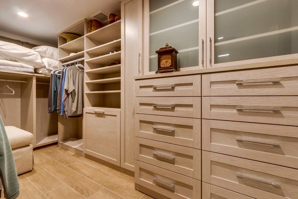 Large contemporary men's walk-in wardrobe in Orange County with glass-front cabinets, light wood cabinets, porcelain floors and beige floor.