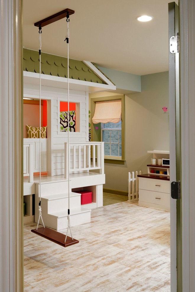 Creative and Unique Playroom - A perfect playroom space for two young girls to grow into.  The space contains a custom made playhouse, complete with hidden trap door, custom built in benches with plenty of toy storage and bench cushions for reading, lounging or play pretend.  In order to mimic an outdoor space, we added an indoor swing.  The side of the playhouse has a small soft area with green carpeting to mimic grass, and a small picket fence.  The tree wall stickers add to the theme.  A huge highlight to the space is the custom designed, custom built craft table with plenty of storage for all kinds of craft supplies.  The rustic laminate wood flooring adds to the cottage theme.
Bob Narod Photography