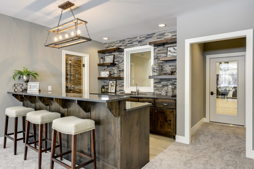 Inspiration for a mid-sized transitional galley seated home bar in Minneapolis with an undermount sink, shaker cabinets, dark wood cabinets, granite benchtops, multi-coloured splashback, porcelain splashback, porcelain floors, grey floor and black benchtop.