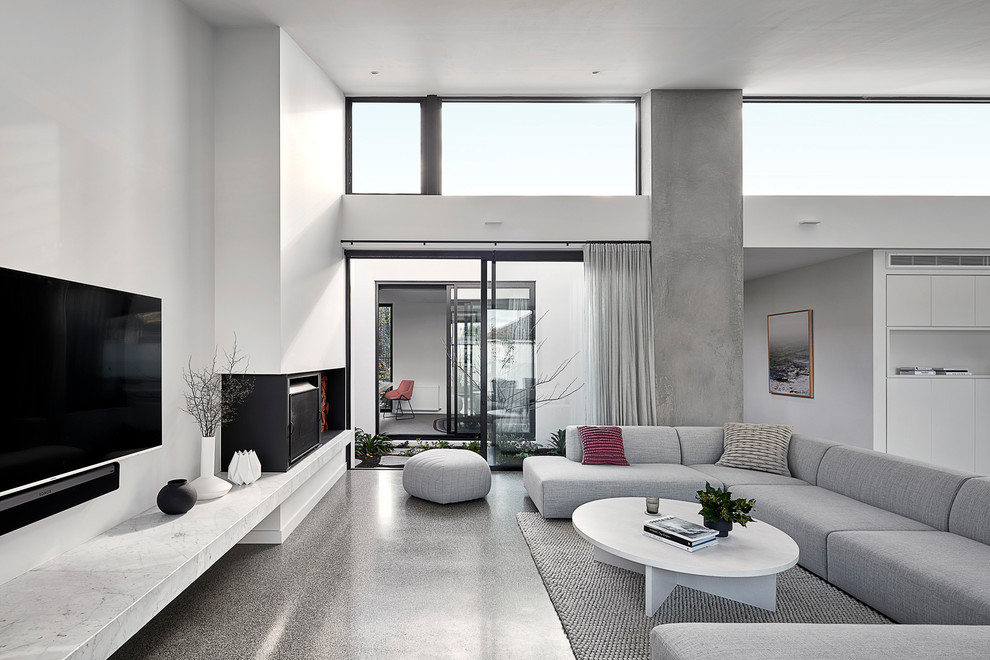Design ideas for a large contemporary formal open concept living room in Melbourne with white walls, concrete floors, a standard fireplace, a metal fireplace surround, a wall-mounted tv and grey floor.