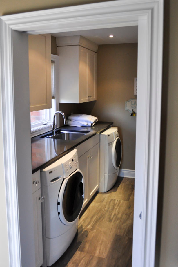 This is an example of a transitional single-wall dedicated laundry room in Toronto with shaker cabinets, white cabinets and medium hardwood floors.