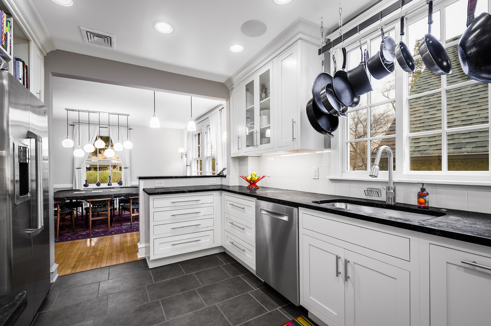 Design ideas for a small transitional u-shaped eat-in kitchen in Philadelphia with an undermount sink, beaded inset cabinets, white cabinets, soapstone benchtops, white splashback, glass tile splashback, stainless steel appliances, porcelain floors and a peninsula.