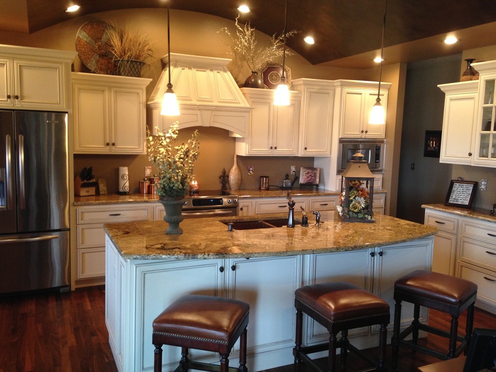Large transitional l-shaped medium tone wood floor and brown floor eat-in kitchen photo with an undermount sink, recessed-panel cabinets, yellow cabinets, laminate countertops, stainless steel appliances, brown walls and two islands