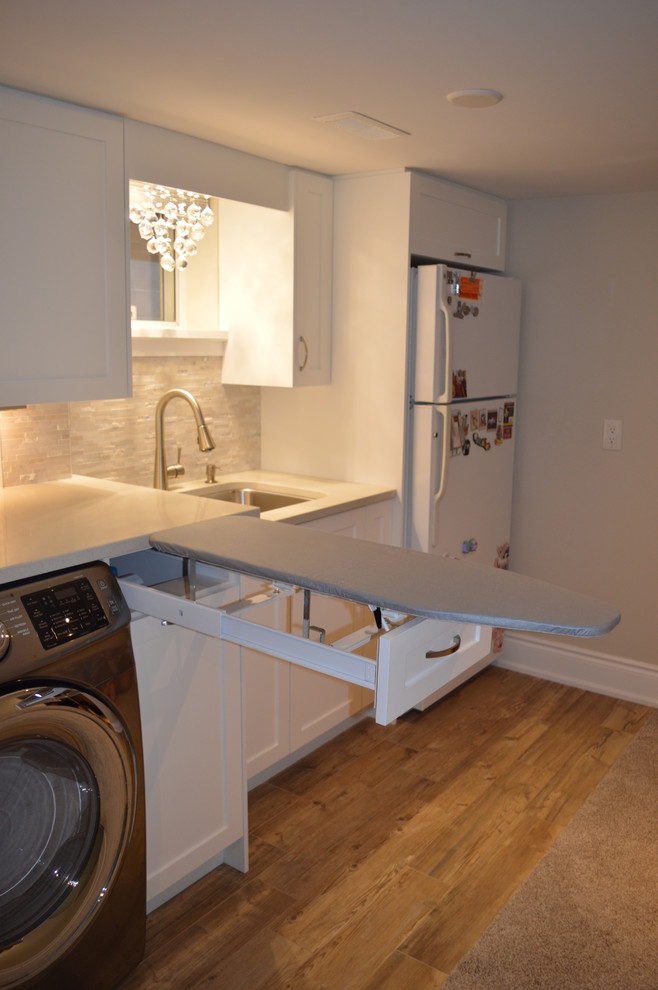 This is an example of a mid-sized transitional single-wall utility room in Toronto with an utility sink, shaker cabinets, white cabinets, quartzite benchtops, grey walls, ceramic floors and a side-by-side washer and dryer.