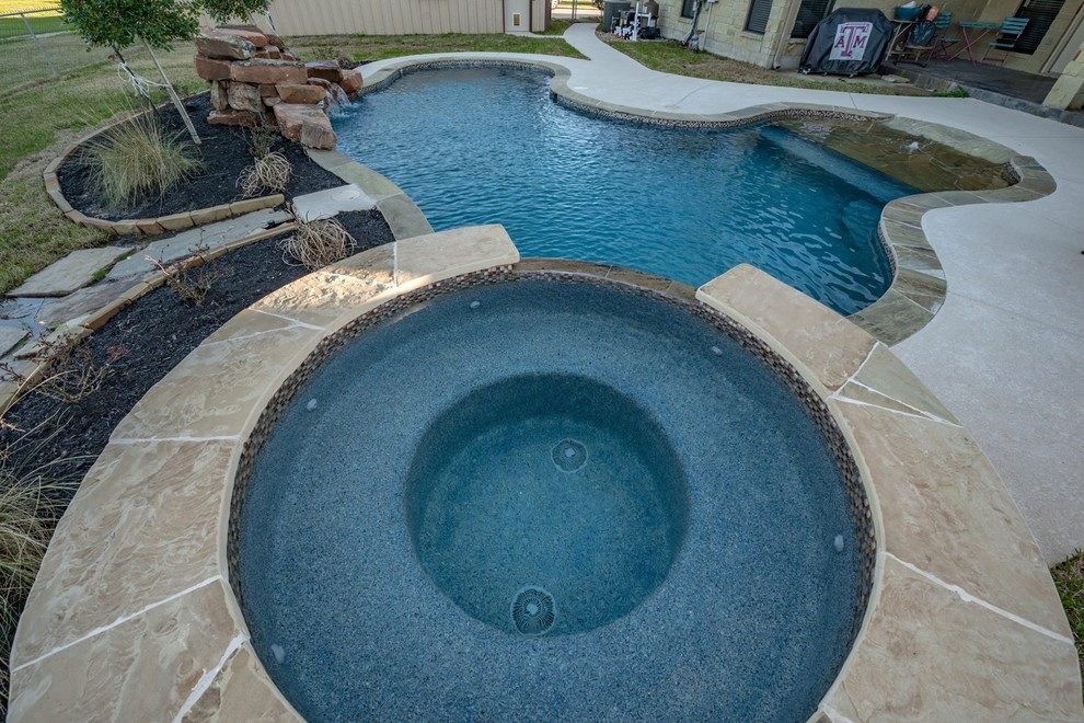 Mid-sized mountain style backyard stone and kidney-shaped natural hot tub photo in Austin
