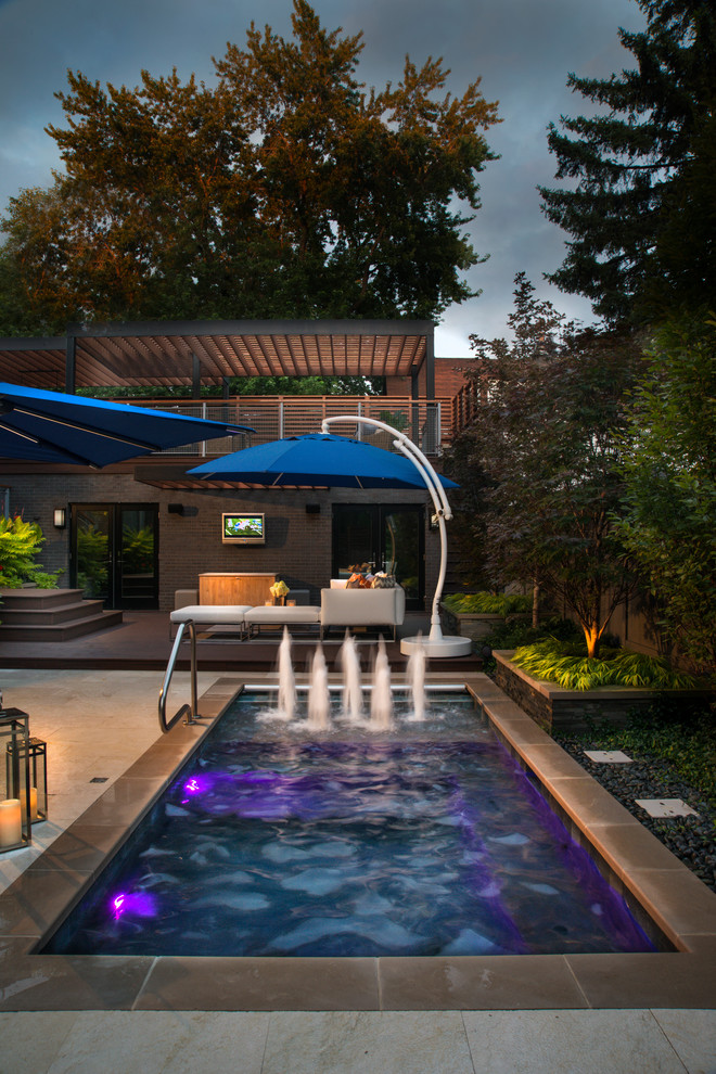This is an example of a small traditional courtyard rectangular lap pool in Chicago with a water feature and natural stone pavers.
