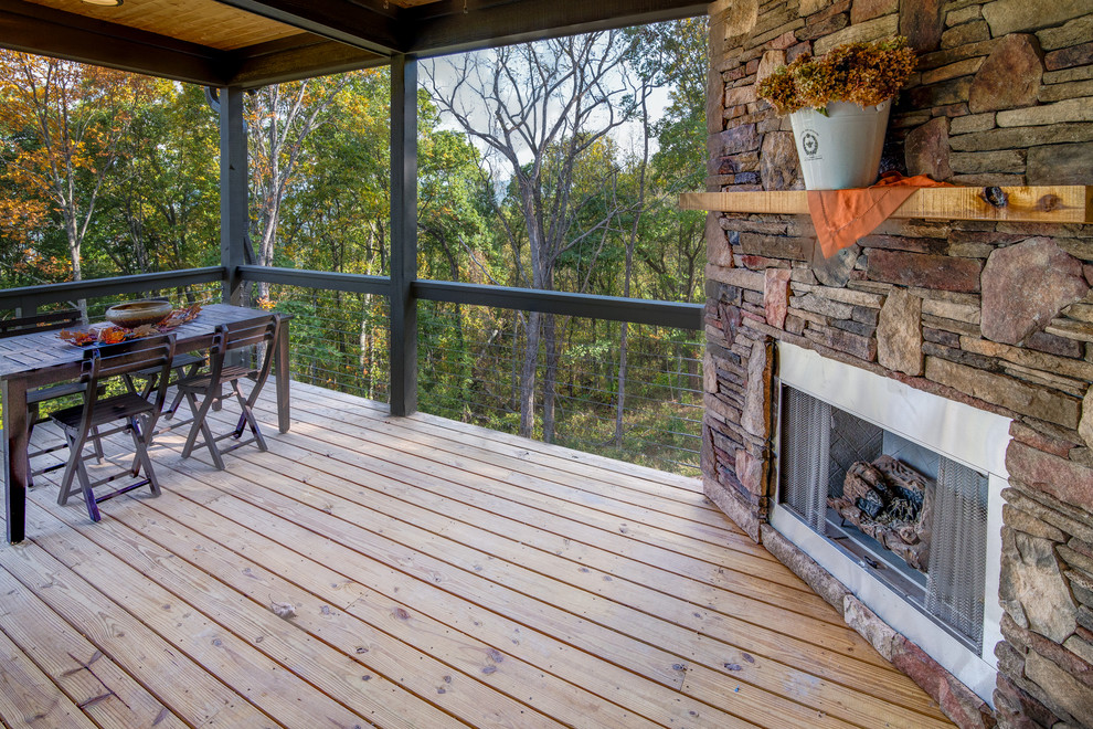 Inspiration for a rustic deck remodel with a roof extension and a fireplace