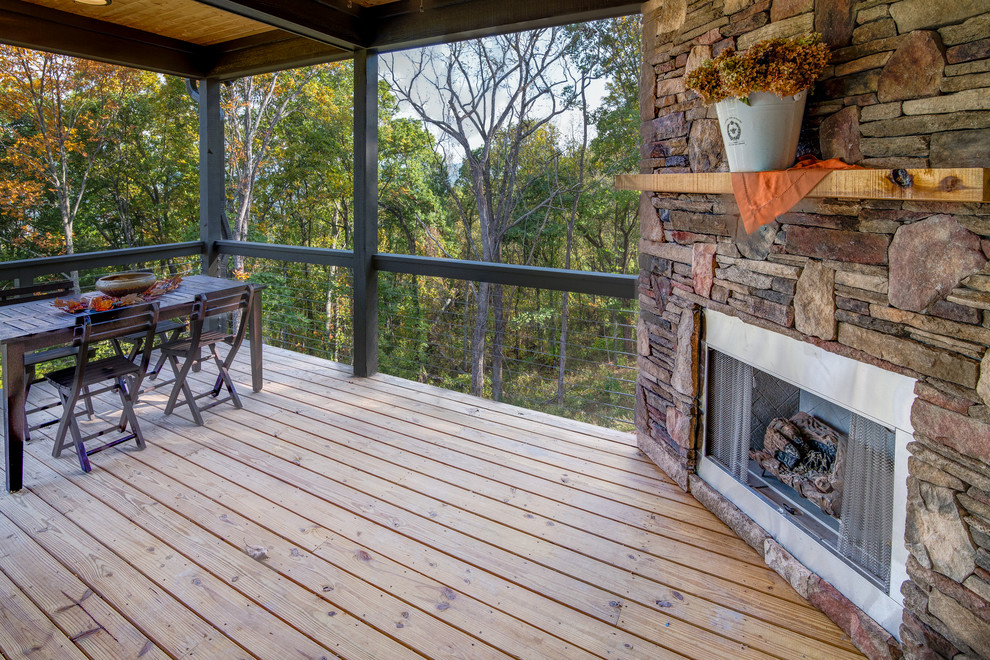Photo of a country deck in Other with a roof extension and a fire feature.