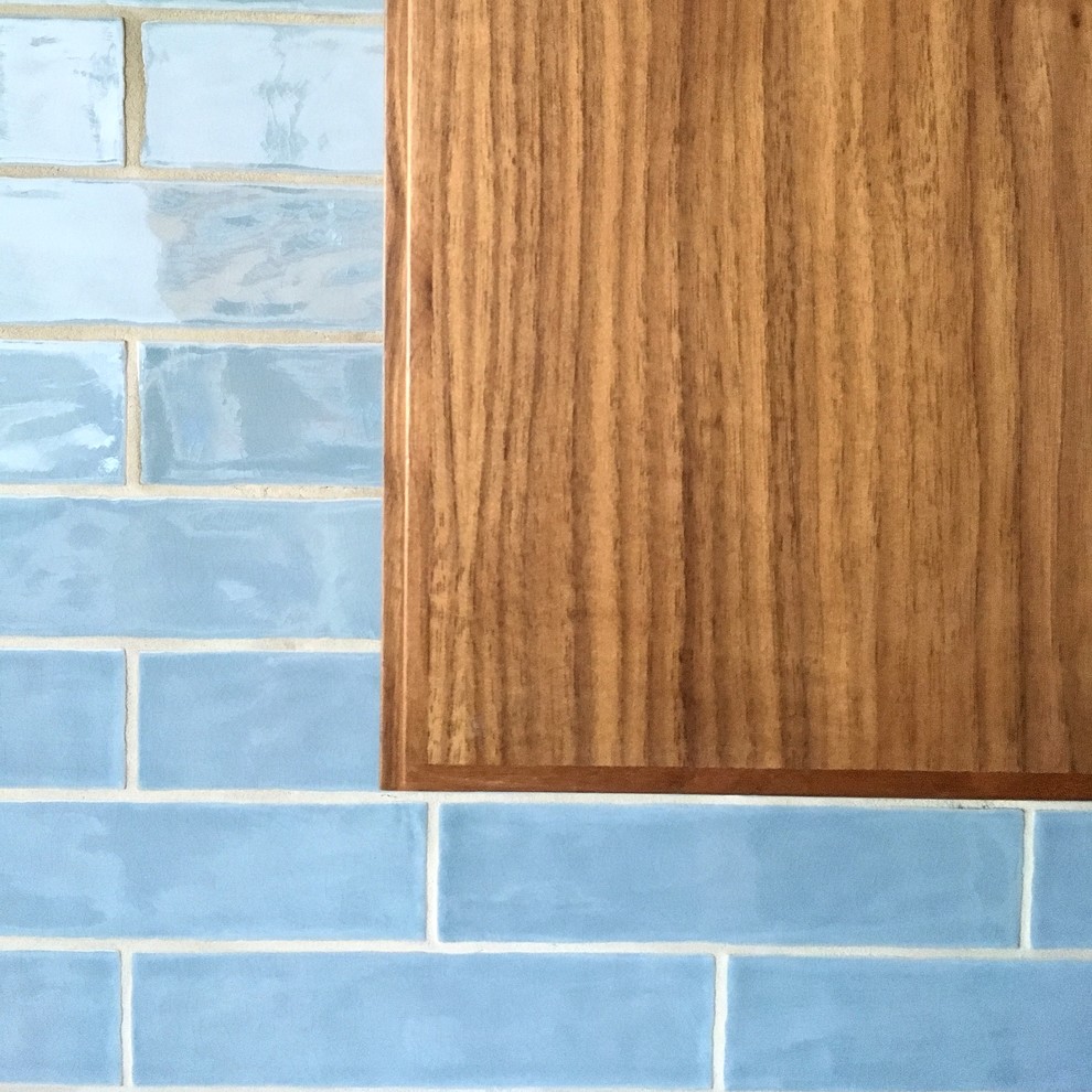 Inspiration for a mid-sized transitional u-shaped kitchen remodel in Austin with flat-panel cabinets, medium tone wood cabinets, blue backsplash, ceramic backsplash, stainless steel appliances and an island