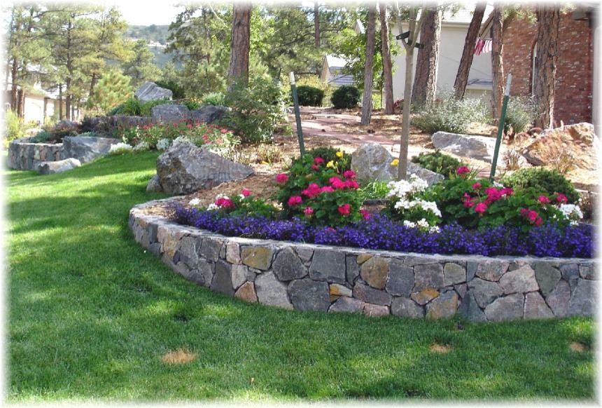 Photo of a mid-sized traditional front yard full sun garden for spring in New York with a retaining wall and mulch.