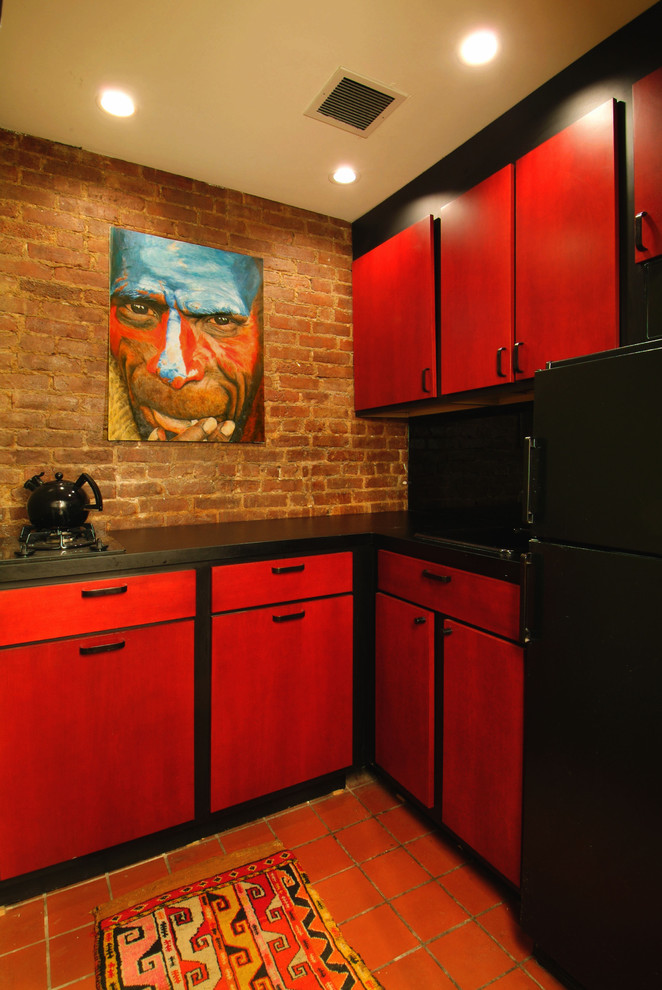 This is an example of a small eclectic l-shaped separate kitchen in New York with an undermount sink, flat-panel cabinets, red cabinets, granite benchtops, black appliances and terra-cotta floors.