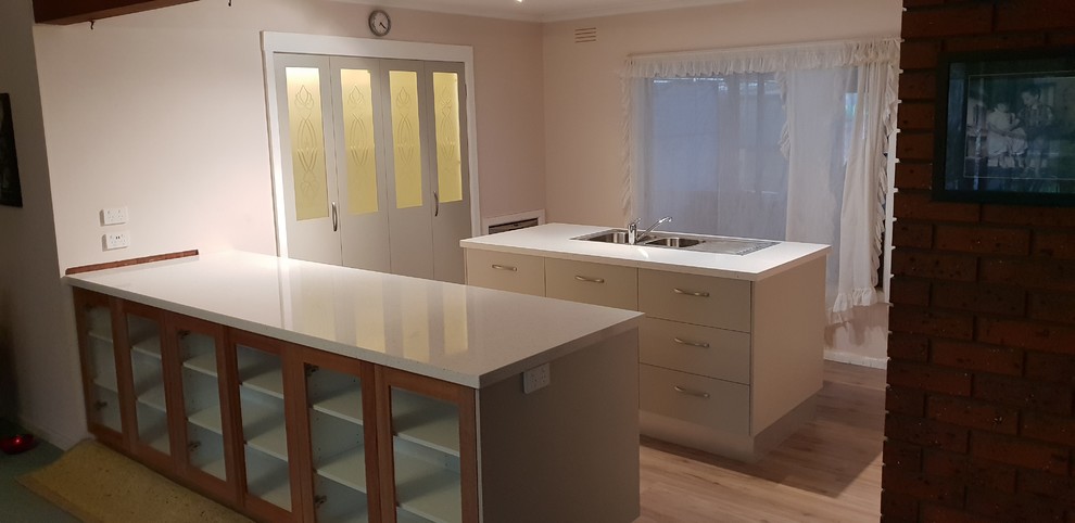 This is an example of a mid-sized contemporary kitchen pantry with a double-bowl sink, solid surface benchtops, with island, flat-panel cabinets and stainless steel appliances.