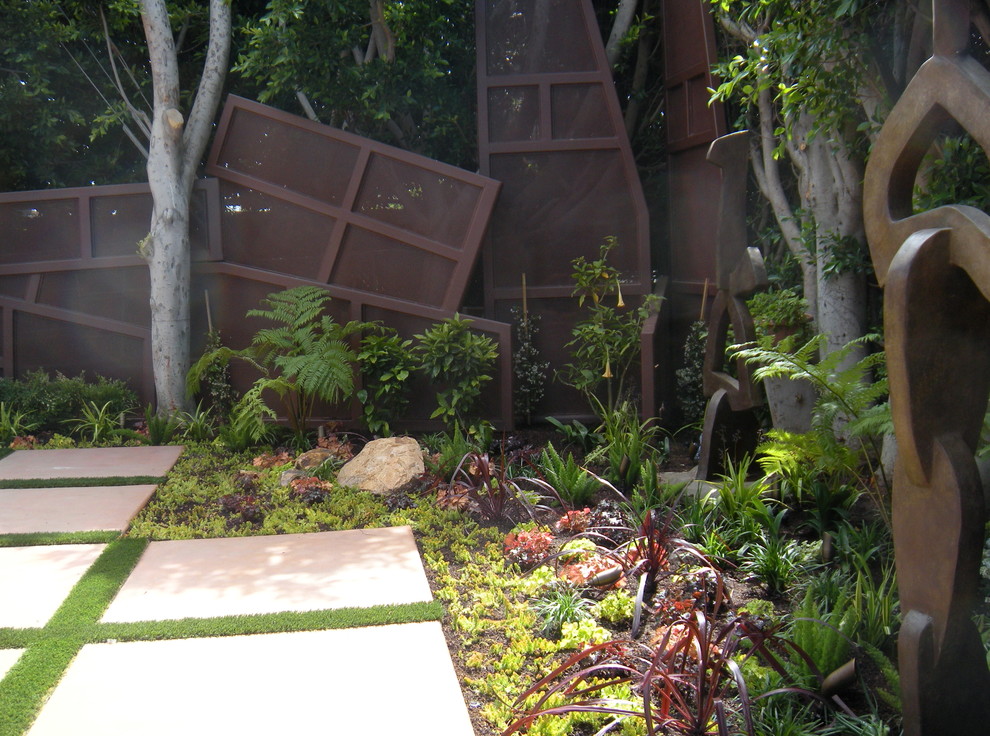 Photo of a large mediterranean backyard shaded garden in Los Angeles with concrete pavers.