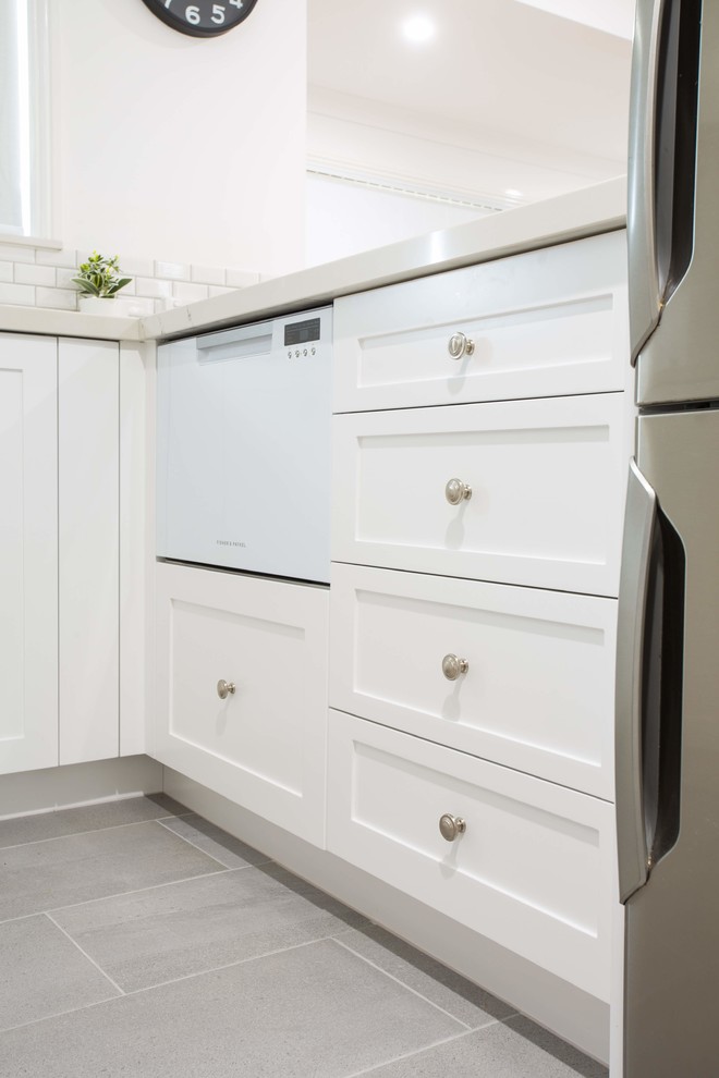 Inspiration for a small traditional u-shaped kitchen pantry in Brisbane with a double-bowl sink, shaker cabinets, white cabinets, quartz benchtops, grey splashback, ceramic splashback, black appliances, porcelain floors, with island, grey floor and white benchtop.