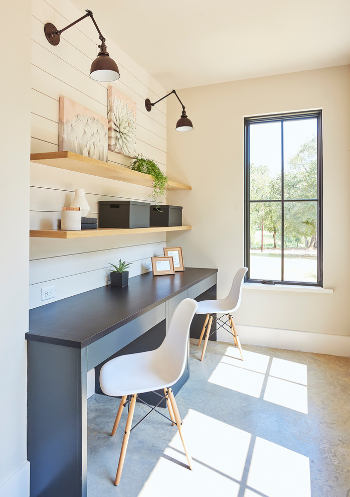 This is an example of a transitional study room in Dallas with white walls, concrete floors, a built-in desk and grey floor.