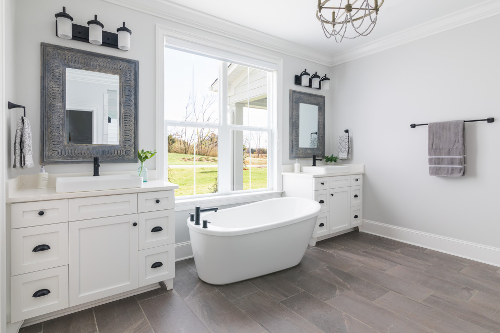 This is an example of a classic ensuite bathroom in Other with shaker cabinets, white cabinets, a freestanding bath, white tiles, white walls, porcelain flooring, a vessel sink, engineered stone worktops, grey floors, white worktops, a single sink and a freestanding vanity unit.