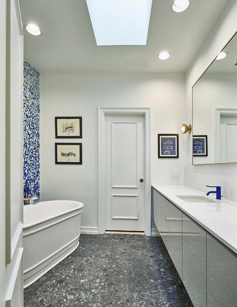 Design ideas for a mid-sized modern kids bathroom in Dallas with flat-panel cabinets, grey cabinets, a freestanding tub, a wall-mount toilet, blue tile, glass sheet wall, white walls, cork floors, an undermount sink, quartzite benchtops, a curbless shower, white floor and a hinged shower door.