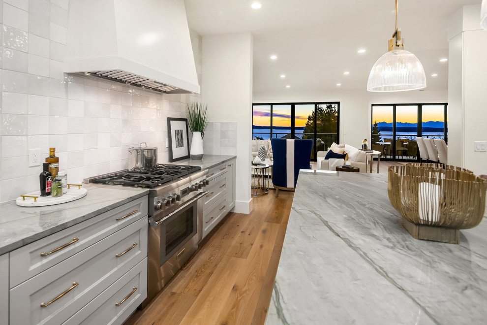 Example of a large transitional l-shaped kitchen design in Seattle with white backsplash and an island