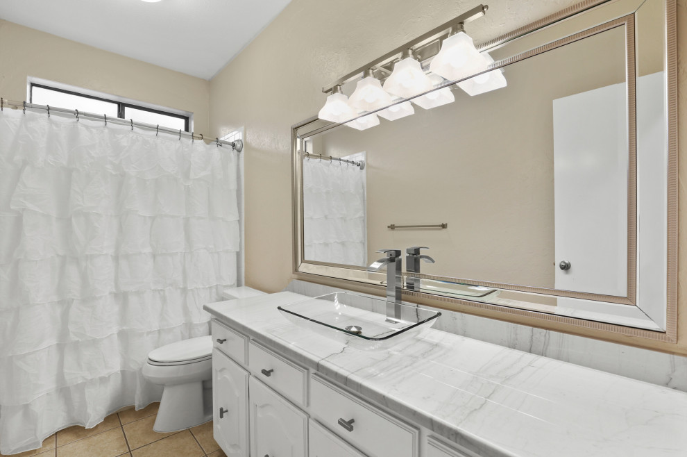 Exempel på ett mellanstort modernt vit vitt badrum med dusch, med luckor med upphöjd panel, vita skåp, ett platsbyggt badkar, en dusch/badkar-kombination, en toalettstol med hel cisternkåpa, beige väggar, klinkergolv i keramik, ett konsol handfat, bänkskiva i kvartsit, beiget golv och dusch med duschdraperi