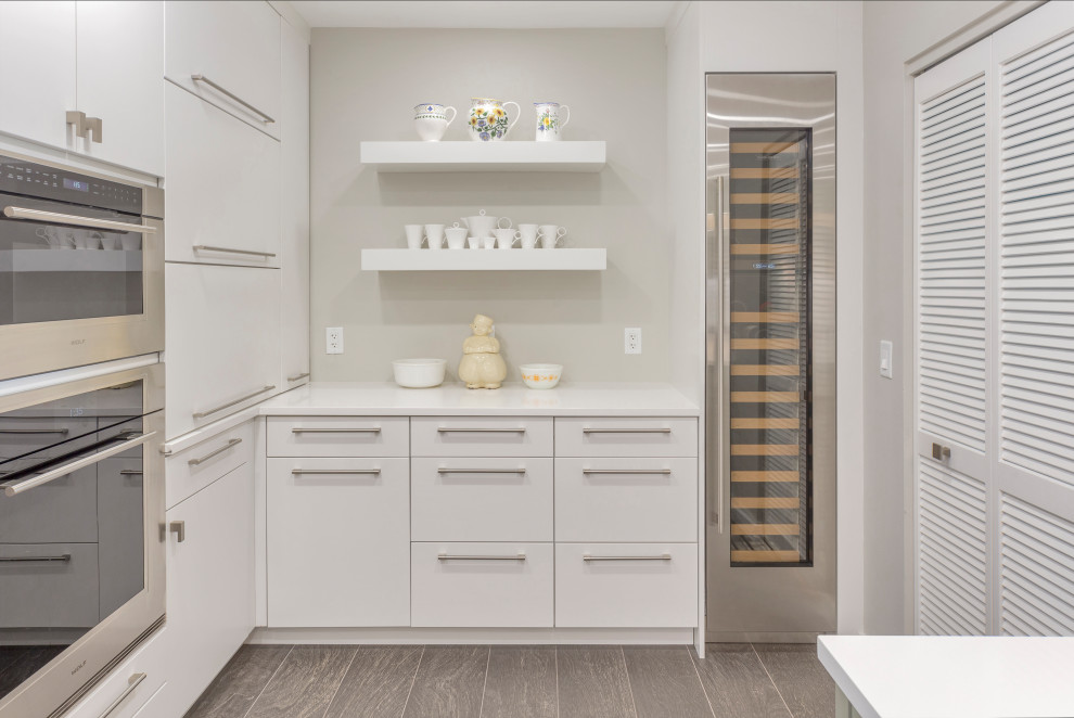 Large minimalist galley light wood floor and gray floor kitchen photo in Tampa with marble countertops, white countertops, flat-panel cabinets, white cabinets and stainless steel appliances