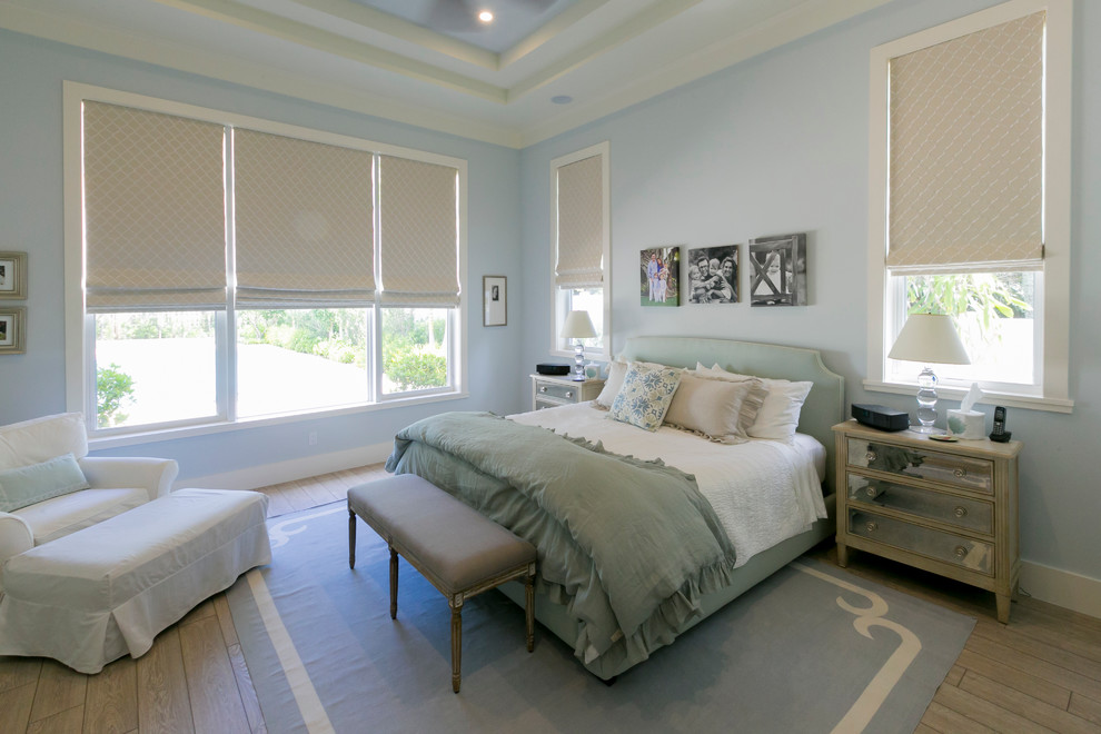 Large transitional master bedroom in Miami with blue walls and light hardwood floors.