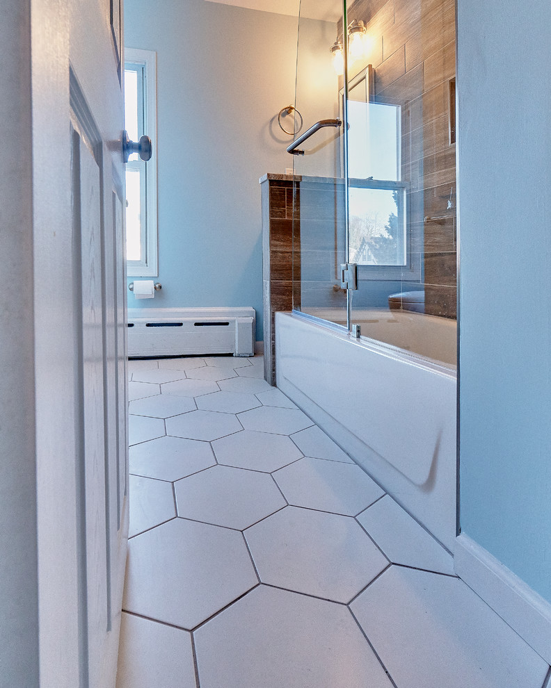 Mid-sized transitional kids bathroom with recessed-panel cabinets, medium wood cabinets, a corner tub, a shower/bathtub combo, a two-piece toilet, brown tile, porcelain tile, brown walls, porcelain floors, an undermount sink, limestone benchtops, grey floor, an open shower and grey benchtops.