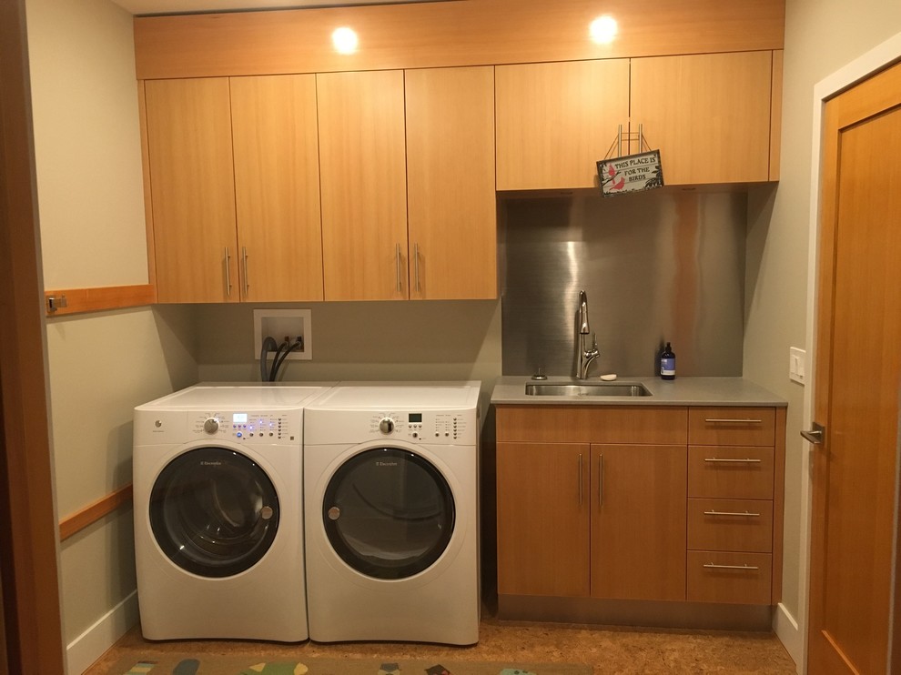 This is an example of a mid-sized transitional single-wall laundry room in Bridgeport with an undermount sink, flat-panel cabinets, medium wood cabinets, solid surface benchtops, beige walls, concrete floors, a side-by-side washer and dryer and grey benchtop.