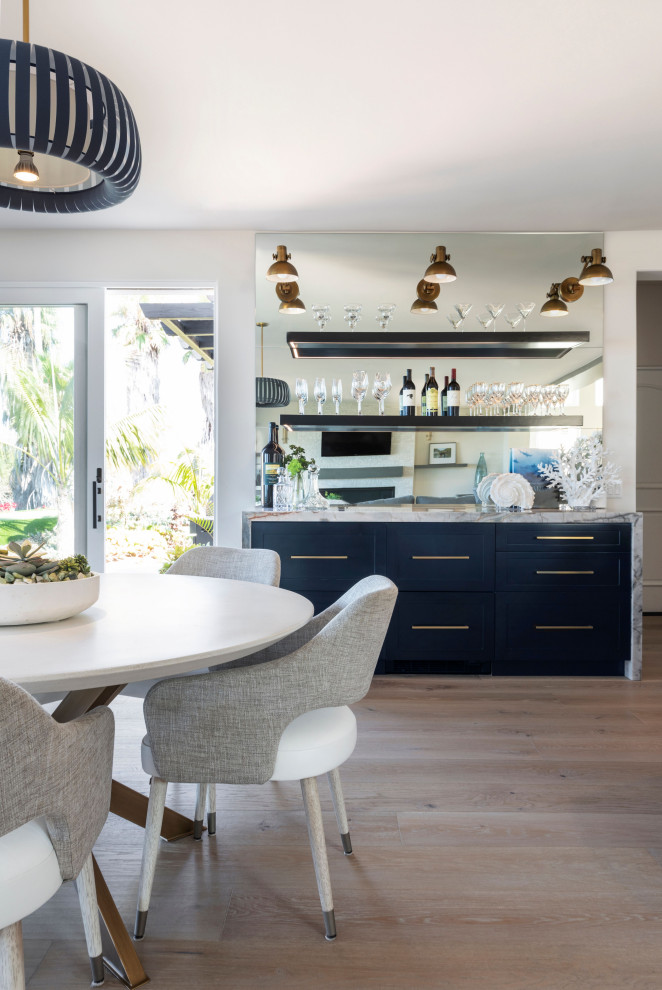 Large modern single-wall home bar in Orange County with shaker cabinets, blue cabinets, quartz worktops, mirror splashback, light hardwood flooring and grey worktops.