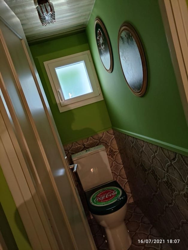 Exemple d'un petit WC et toilettes rétro avec WC à poser, un carrelage marron, des carreaux de céramique, un mur vert, un sol en carrelage de céramique et un sol marron.
