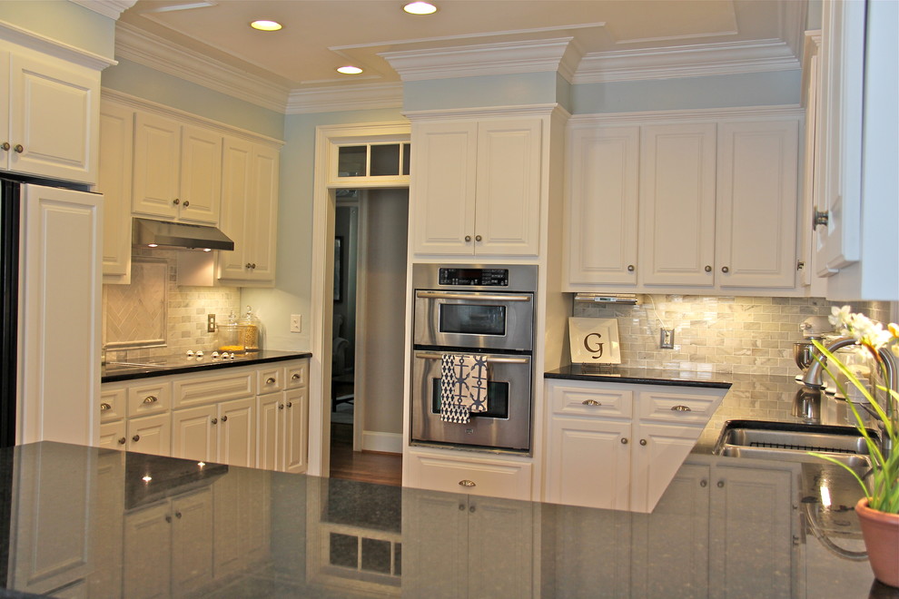 Inspiration for a mid-sized coastal u-shaped medium tone wood floor enclosed kitchen remodel with raised-panel cabinets, white cabinets, granite countertops, white backsplash, subway tile backsplash, stainless steel appliances and an undermount sink