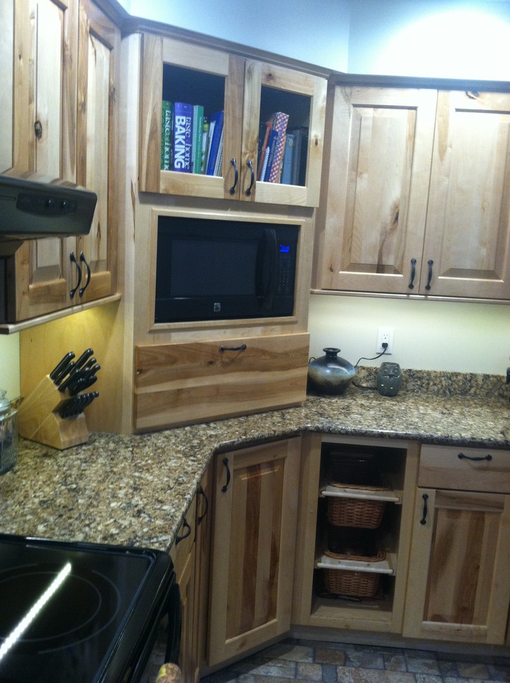 Mid-sized mountain style l-shaped ceramic tile eat-in kitchen photo with an undermount sink, raised-panel cabinets, light wood cabinets, quartz countertops, black appliances and an island