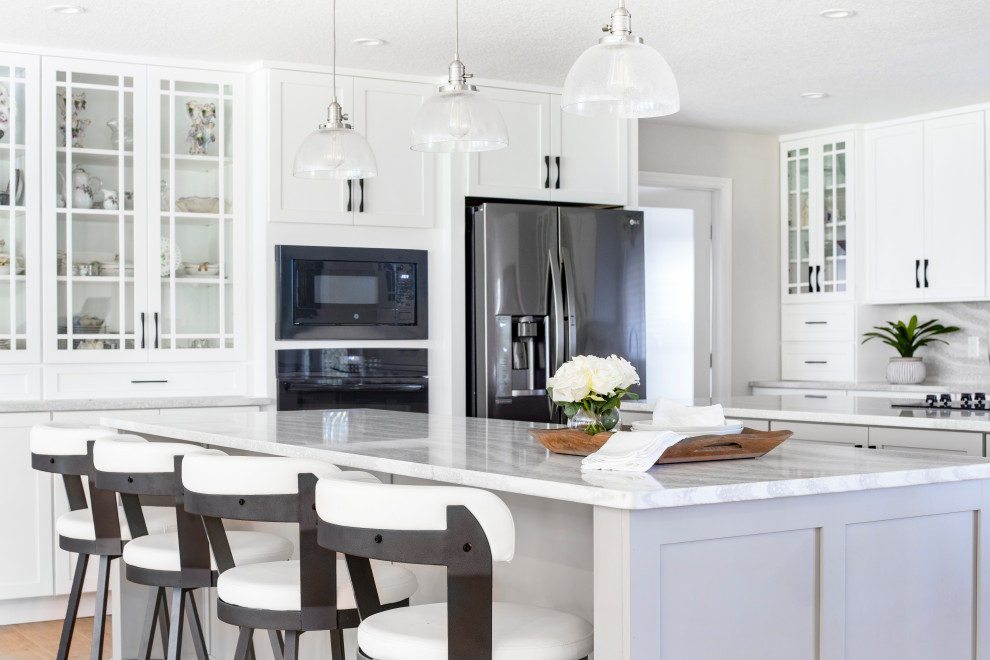 Huge transitional l-shaped open concept kitchen photo in Orlando with shaker cabinets, white cabinets, quartz countertops, white backsplash, quartz backsplash, black appliances, two islands and white countertops