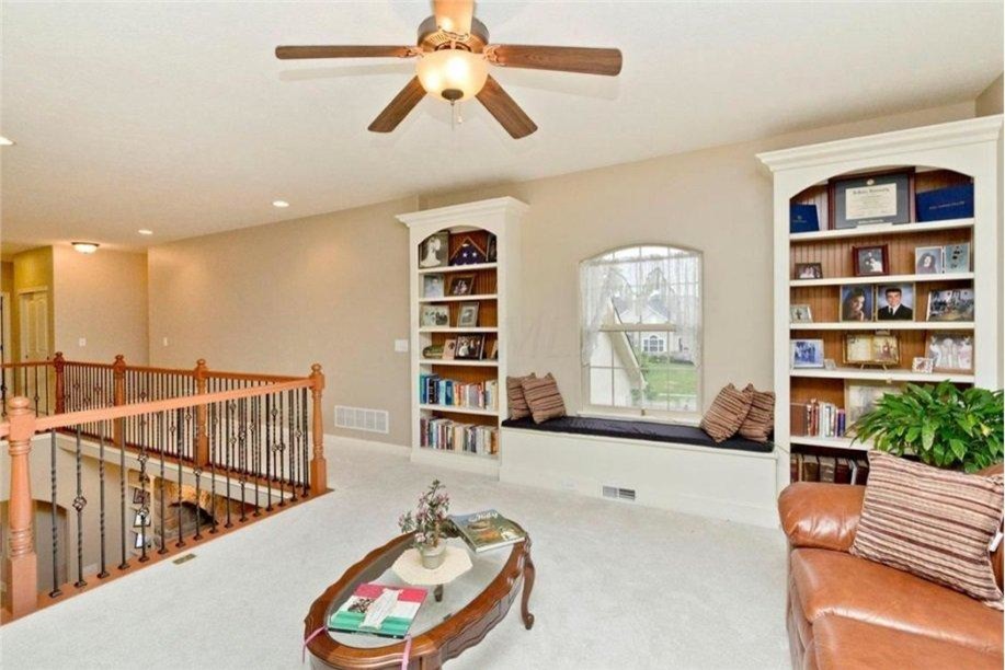 Photo of a large traditional loft-style family room in Columbus with a library, beige walls, light hardwood floors, no fireplace and a built-in media wall.