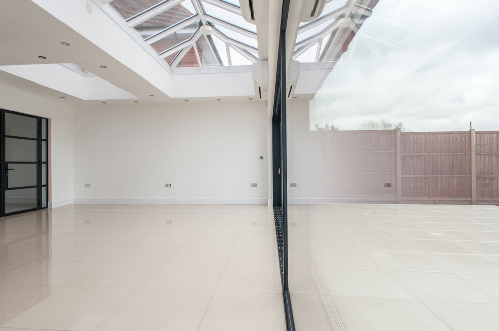 This is an example of a large modern open plan dining room in London with white walls and ceramic flooring.