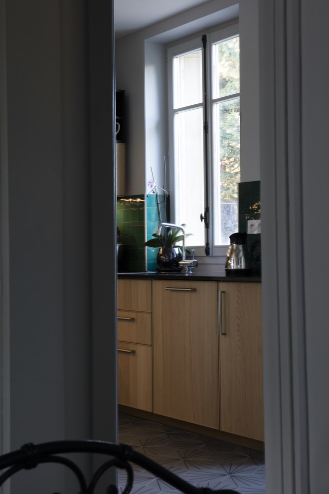 This is an example of a mid-sized eclectic u-shaped separate kitchen in Paris with an integrated sink, beaded inset cabinets, light wood cabinets, granite benchtops, green splashback, terra-cotta splashback, panelled appliances, concrete floors, no island and grey floor.