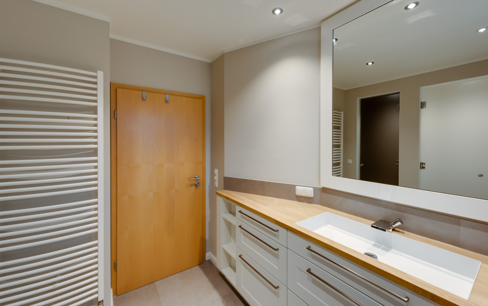 Klassisk inredning av ett mellanstort beige beige badrum med dusch, med luckor med profilerade fronter, vita skåp, ett hörnbadkar, våtrum, en vägghängd toalettstol, vit kakel, beige väggar, ett nedsänkt handfat, beiget golv och dusch med skjutdörr