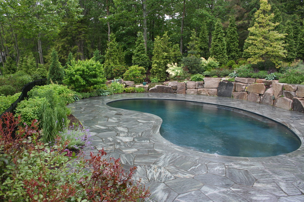 Photo of a traditional kidney-shaped pool in Manchester with natural stone pavers.