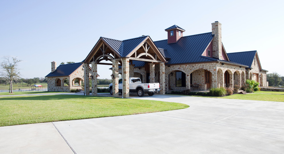 Large traditional beige house exterior in Houston with stone veneer and a gable roof.