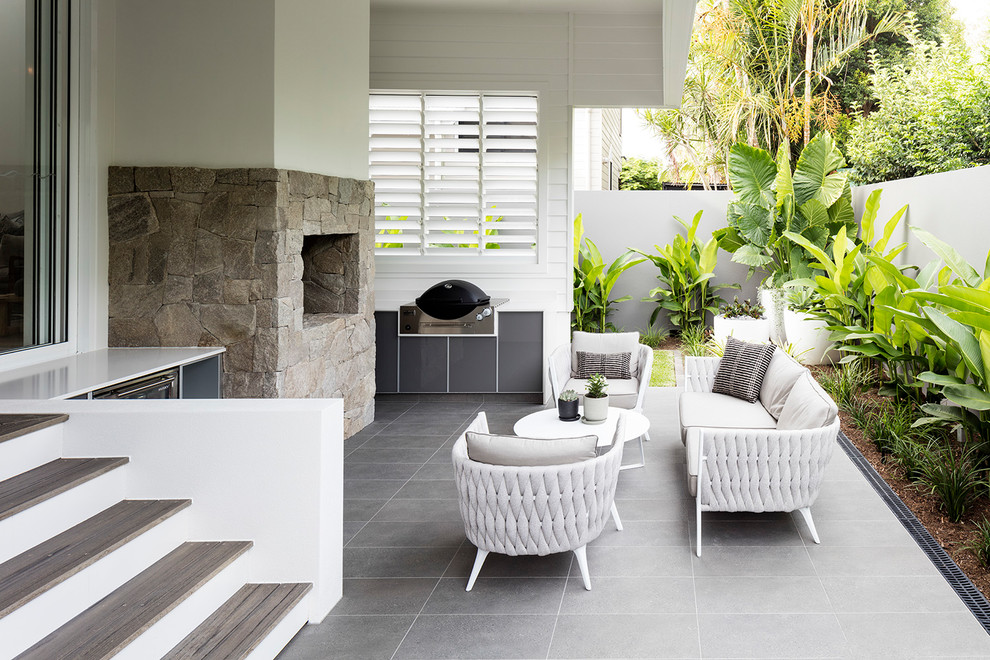 Beach style patio in Sunshine Coast with with fireplace, tile and a roof extension.