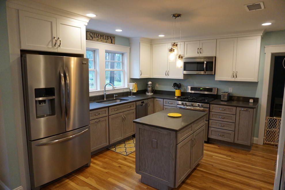 Eat-in kitchen - mid-sized transitional u-shaped medium tone wood floor eat-in kitchen idea in Boston with an undermount sink, shaker cabinets, gray cabinets, quartz countertops, black backsplash, stainless steel appliances and an island