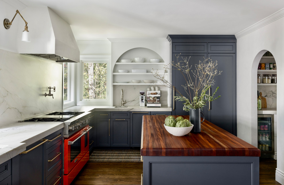 This is an example of a transitional l-shaped kitchen in Seattle with an undermount sink, recessed-panel cabinets, blue cabinets, white splashback, stone slab splashback, panelled appliances, dark hardwood floors, with island, brown floor and white benchtop.