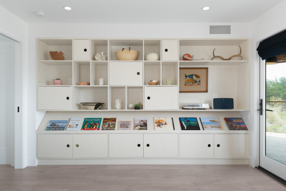 Photo of a mid-sized beach style enclosed family room in Other with a library, white walls, no tv and brown floor.