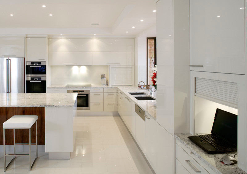 Inspiration for an u-shaped eat-in kitchen in Sydney with a drop-in sink, flat-panel cabinets, white cabinets, solid surface benchtops, white splashback, glass sheet splashback, stainless steel appliances, ceramic floors and with island.