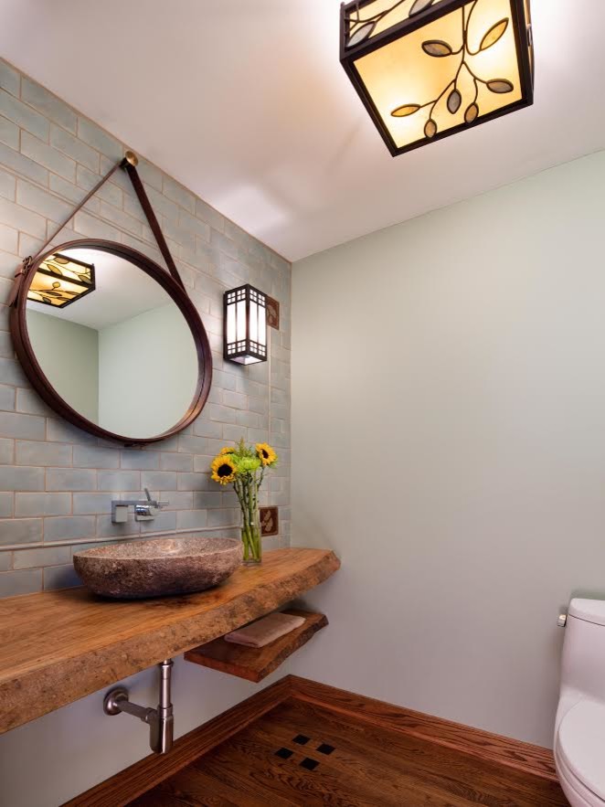 Photo of a mid-sized transitional powder room in Chicago with a one-piece toilet, blue tile, subway tile, blue walls, medium hardwood floors, a vessel sink and wood benchtops.
