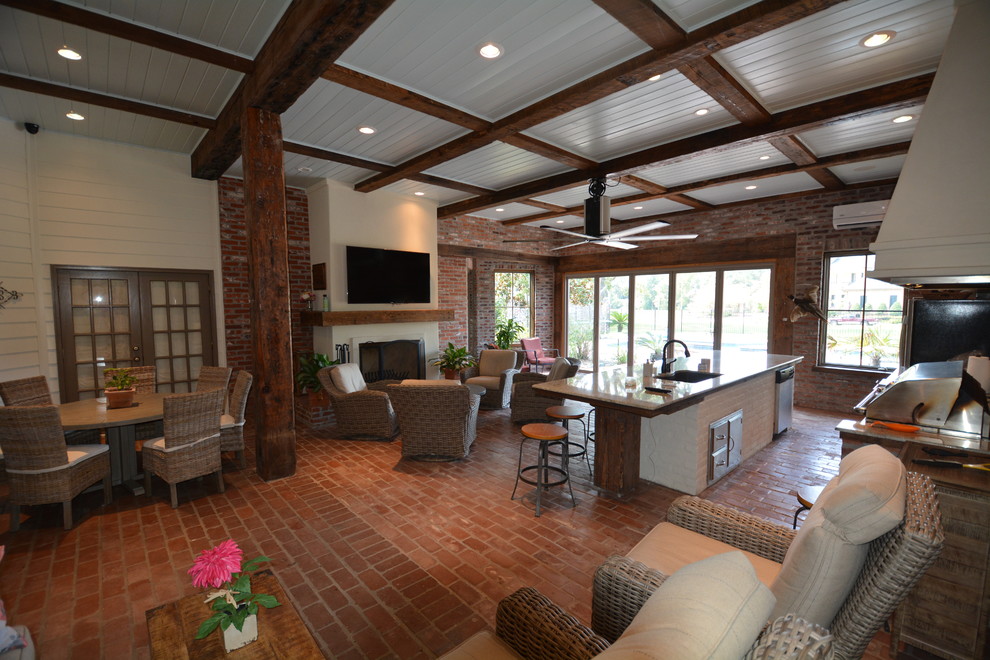 Photo of a large industrial sunroom in New Orleans with brick floors, a standard fireplace, a plaster fireplace surround and a standard ceiling.