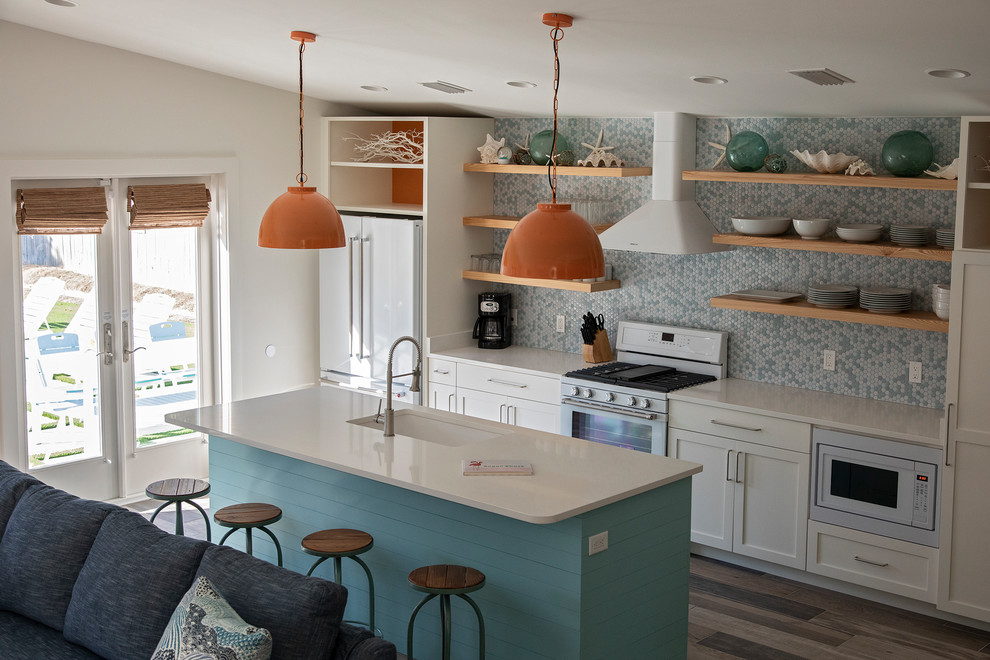 Mid-sized midcentury single-wall open plan kitchen in Miami with an undermount sink, recessed-panel cabinets, turquoise cabinets, quartzite benchtops, multi-coloured splashback, ceramic splashback, white appliances, ceramic floors, with island, brown floor and white benchtop.