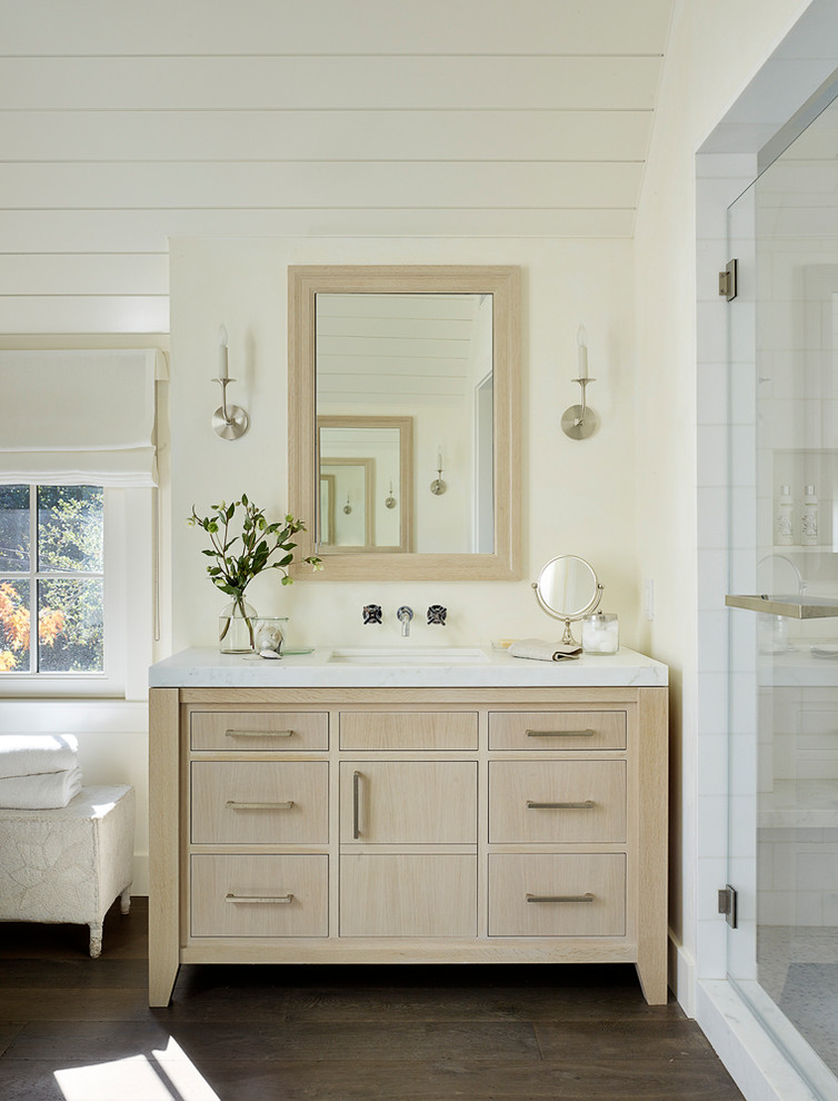 This is an example of a country bathroom in San Francisco with light wood cabinets, an alcove shower, white walls, dark hardwood floors, an undermount sink, brown floor, a hinged shower door, white benchtops and flat-panel cabinets.